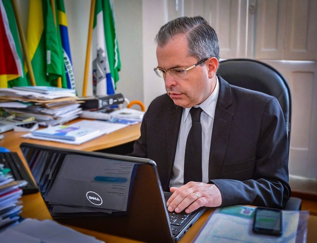Dr. Julio Cesar em seu escritório em Rio Grande, RS, trabalhando em seu notebook, demonstrando profissionalismo e dedicação como advogado.